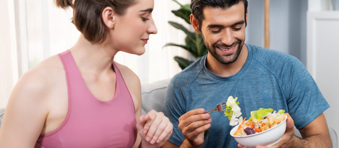 Healthy sporty and vegetarian couple in sportswear with a bowl of fruit and vegetable. Healthy cuisine nutrition and vegan lifestyle for fitness body physique at gaiety home concept.